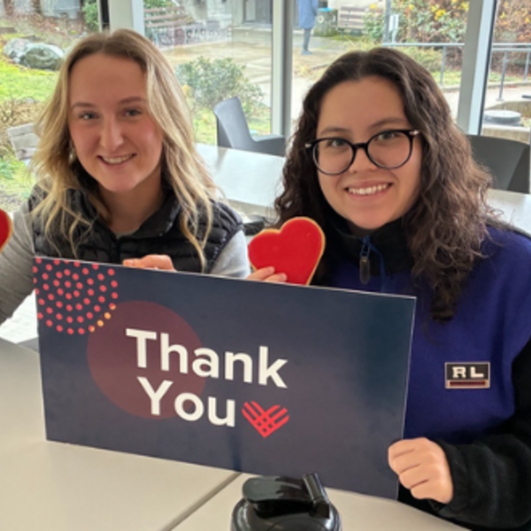 two students smiling and holding a thank you sign