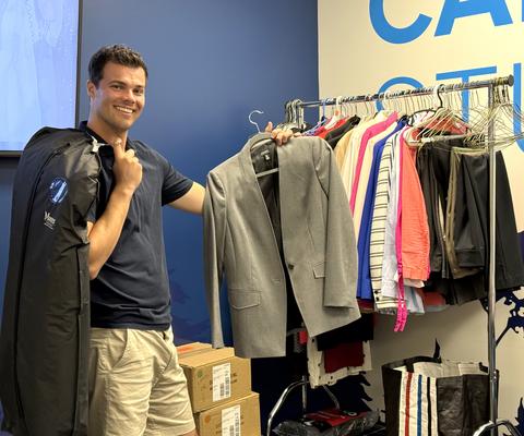 Joel stands next to a rack of clothes